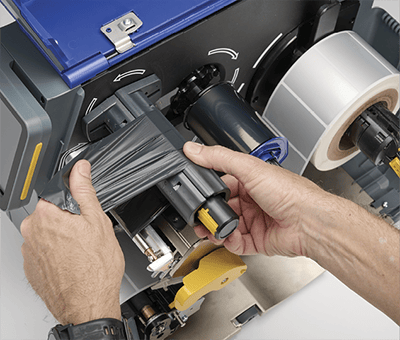 Un employé chargeant rapidement un nouveau ruban encreur dans une imprimante i7500.