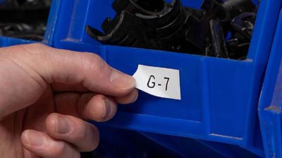 Une personne ajuste une étiquette amovible sur un bac.