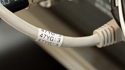 Une étiquette Brady en nylon polyvalente, sur laquelle est imprimé le texte « 47YG 3 », appliquée sur un câble Ethernet Cat-5e.